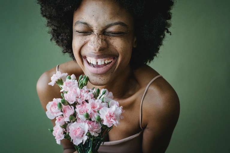 Close up of a black woman with a bouquet of flowers who is embodying the DBT concept of a life worth living.