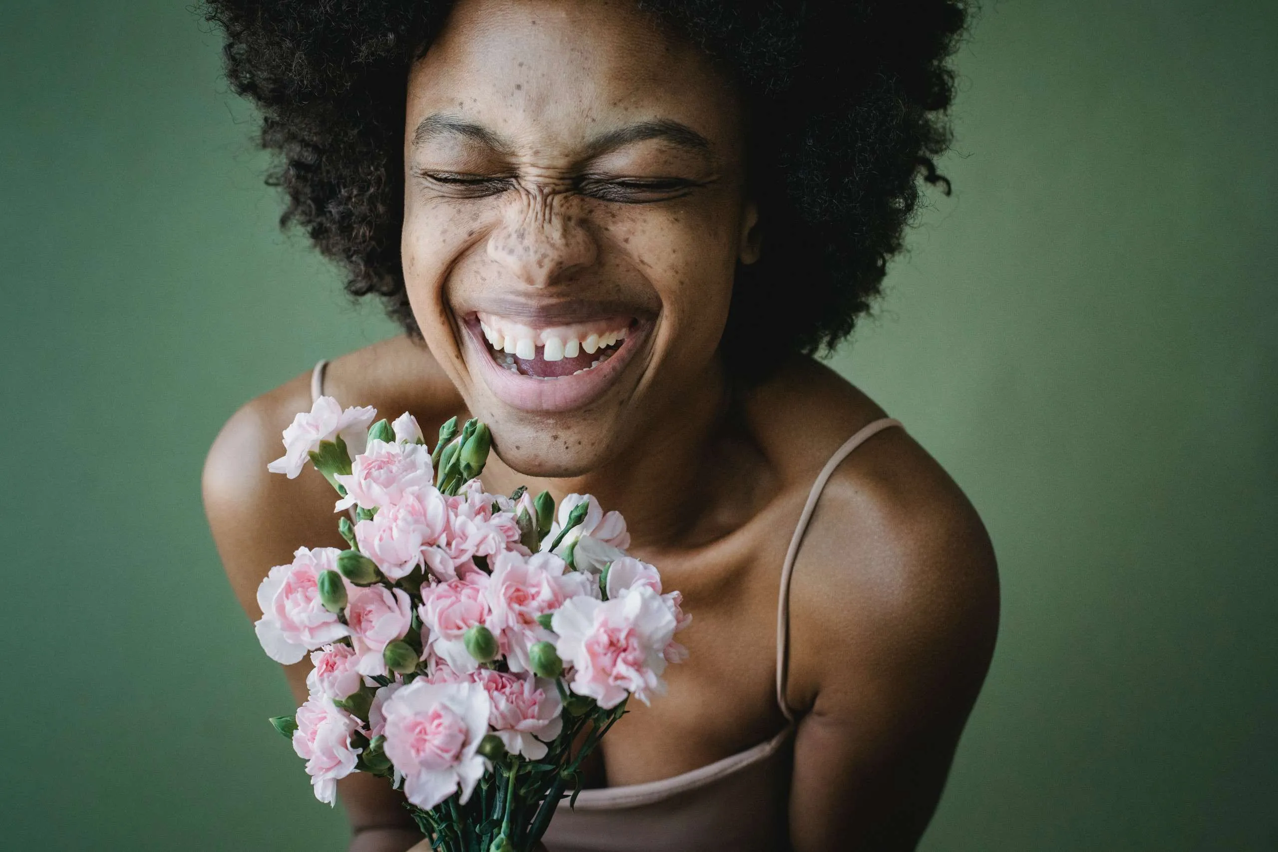 Close up of a black woman with a bouquet of flowers who is embodying the DBT concept of a life worth living.