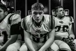 Teen football player sitting quietly in a locker room, illustrating overcontrol in the undercontrol vs. overcontrol spectrum.